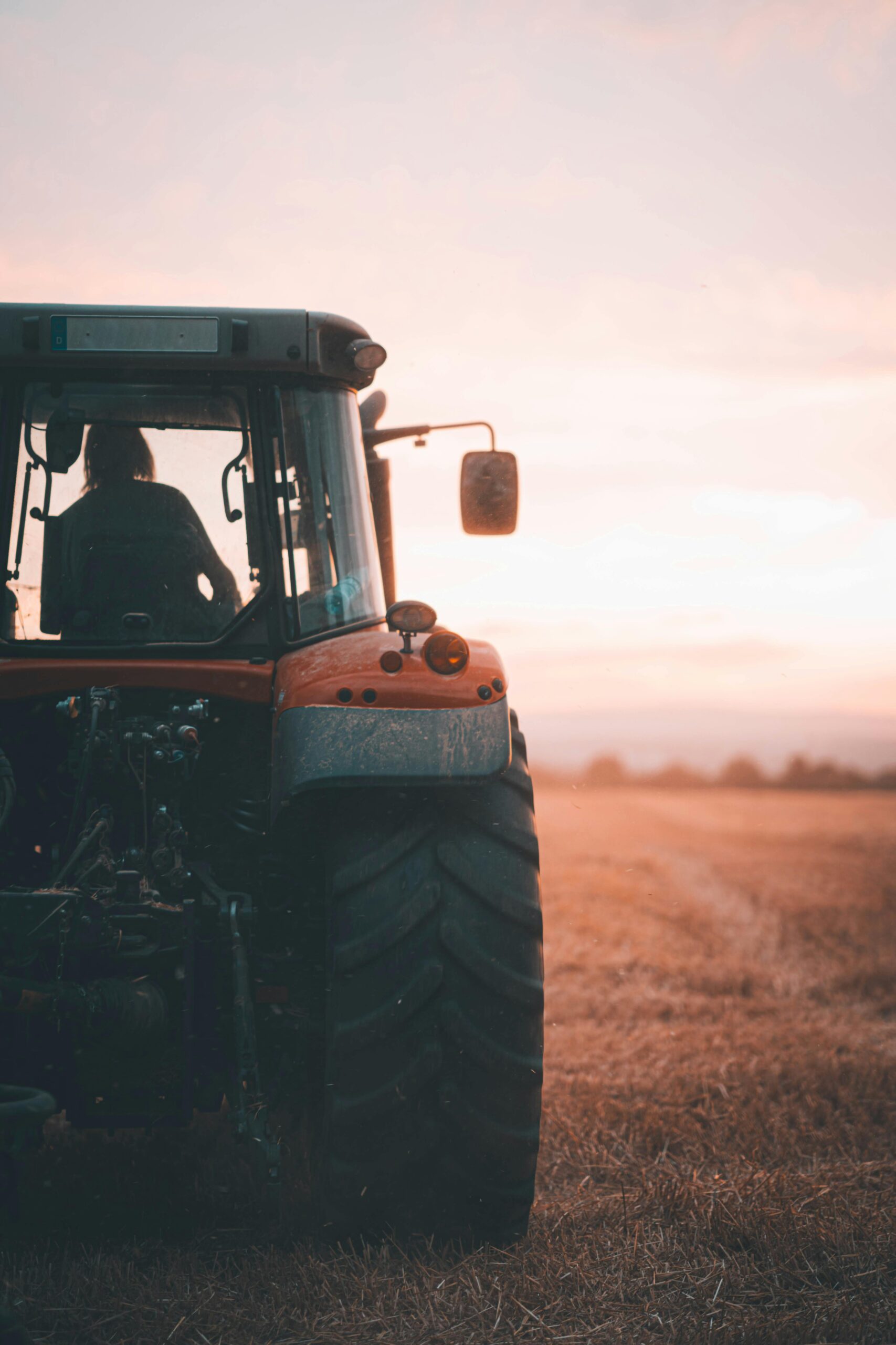 A tractor sits in an open field at sunset, showcasing agriculture's beauty.